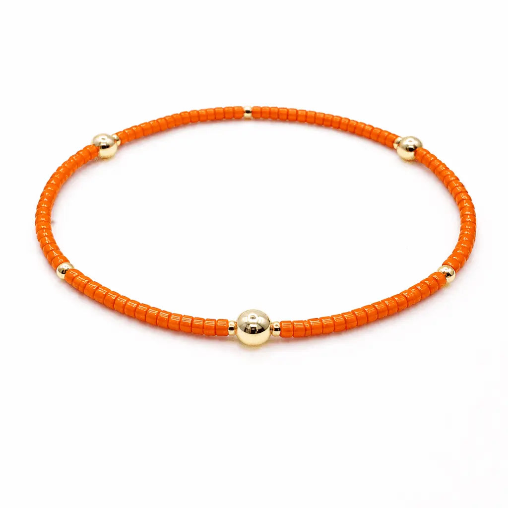 Orange and gold filled jewelry bracelet with "Game Day" engraved, designed by erin gray, featuring vibrant colors and detailed craftsmanship.