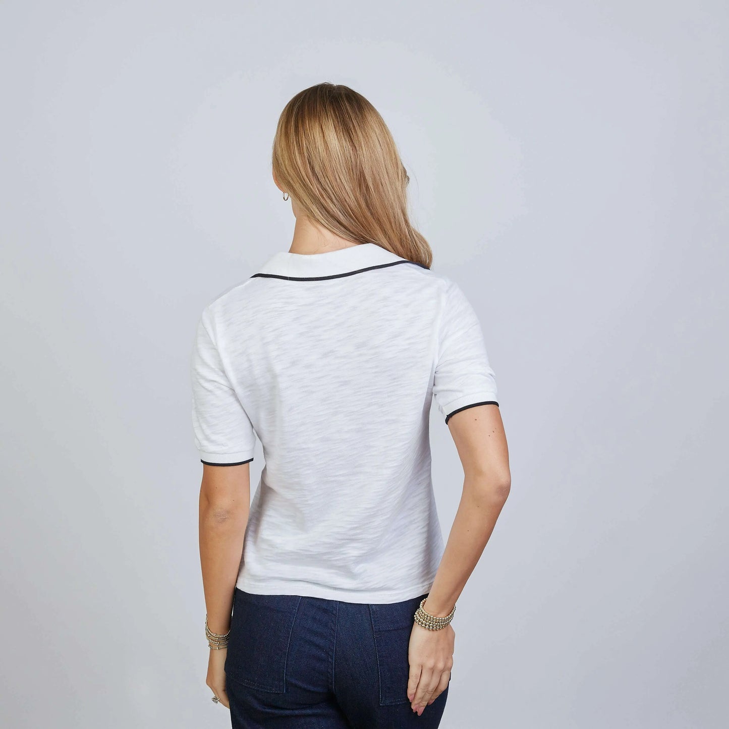 White Piper Polo shirt by erin gray with black contrast piping and short sleeves, styled for casual or smart-casual wear.