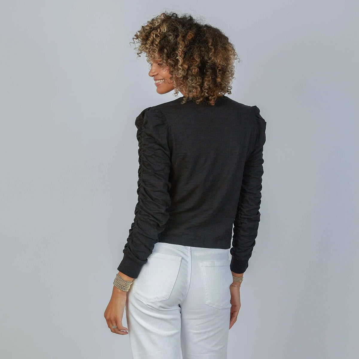 Black Elle Ruched Long Sleeve Tee by erin gray, showing the fitted long-sleeve top with ruched details on a model.