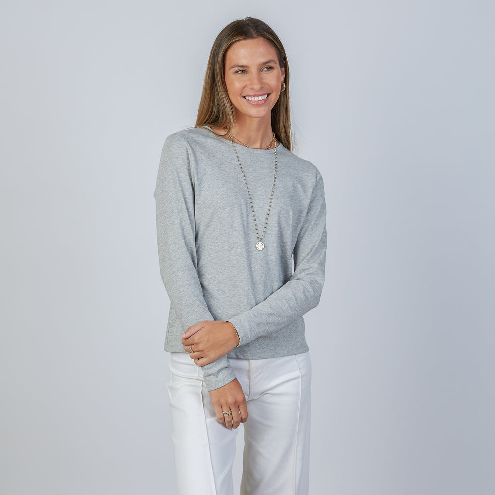 Woman wearing an erin gray light heathered gray classic long-sleeve shirt and white pants against a light gray background