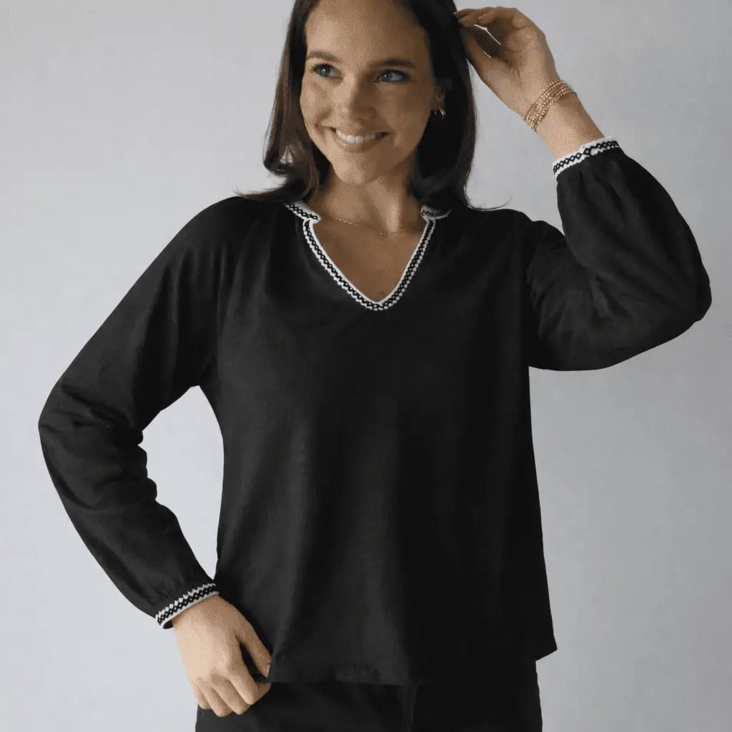 Black long sleeve embroidered top by erin gray with white daisy stitching, stylish and casual women's apparel.