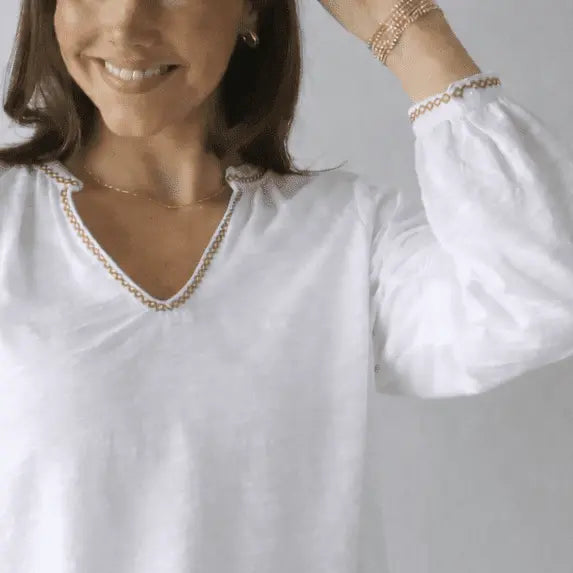 White long sleeve embroidered top by erin gray with daisy pattern and khaki stitching, stylish and casual apparel.