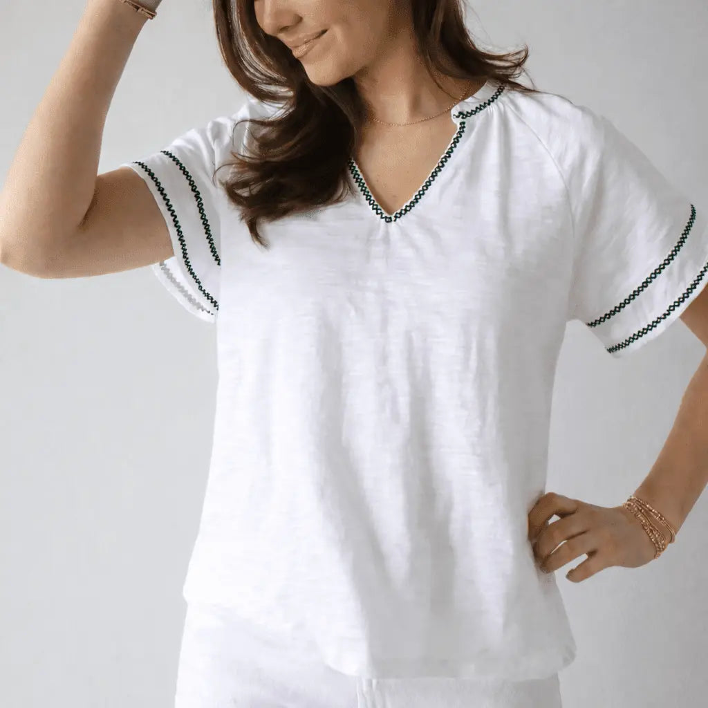 White short sleeve apparel top with daisy embroidery and dark green stitching by erin gray.