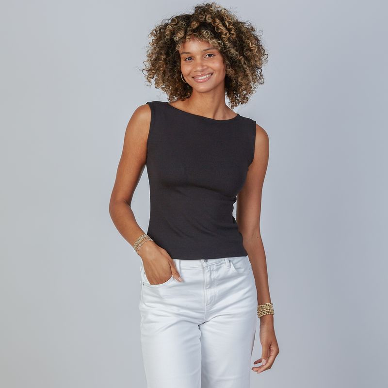 Woman wearing an erin gray design Havana black sleeveless top and white jeans against a gray background
