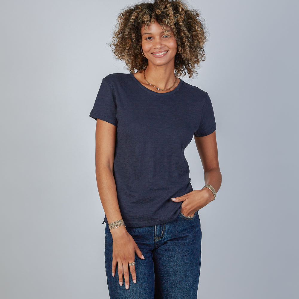 Woman wearing an erin gray design navy blue jeans crew tee and jeans against a gray background