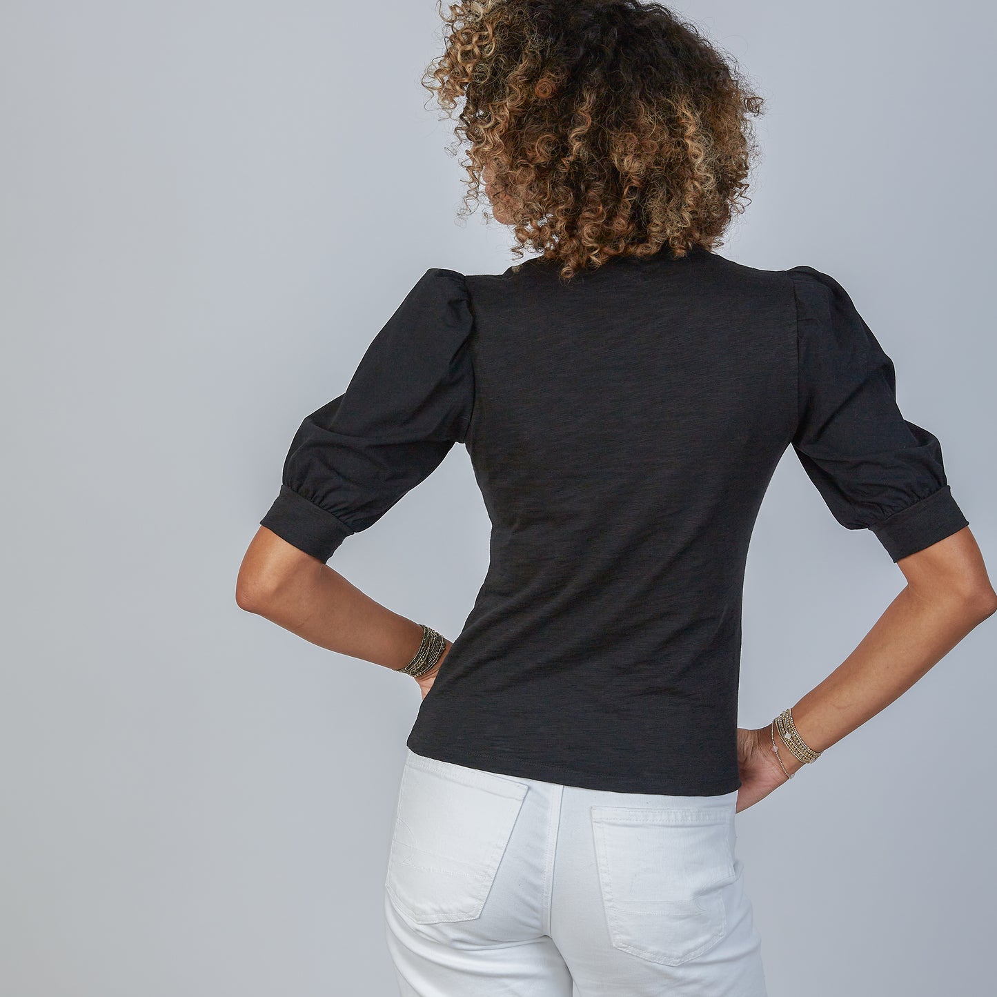 Woman wearing an erin gray black Kate blouse with puffed sleeves against a gray background