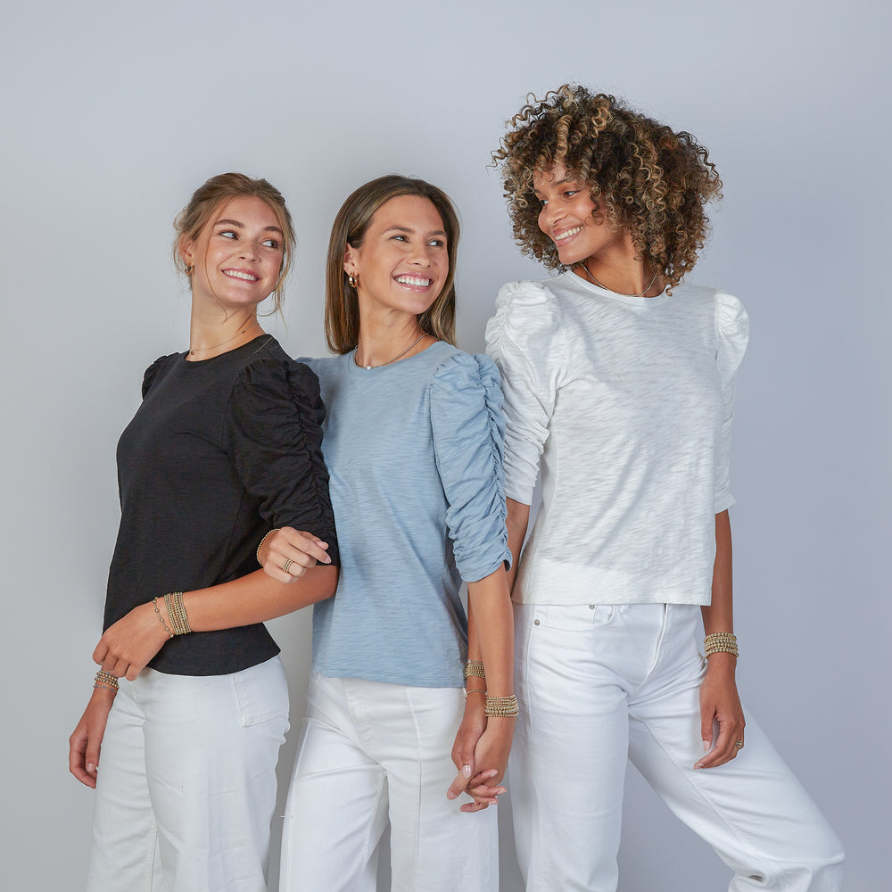 
                      
                        Three women wearing erin gray design sophie shirts in three different colors with white jeans and a plain background
                      
                    