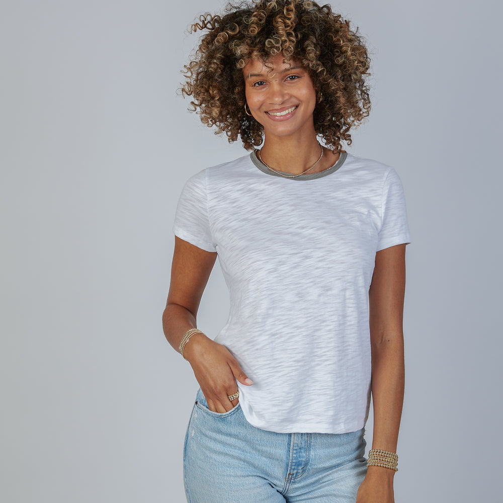 Woman wearing a white t-shirt and blue jeans against a plain background
