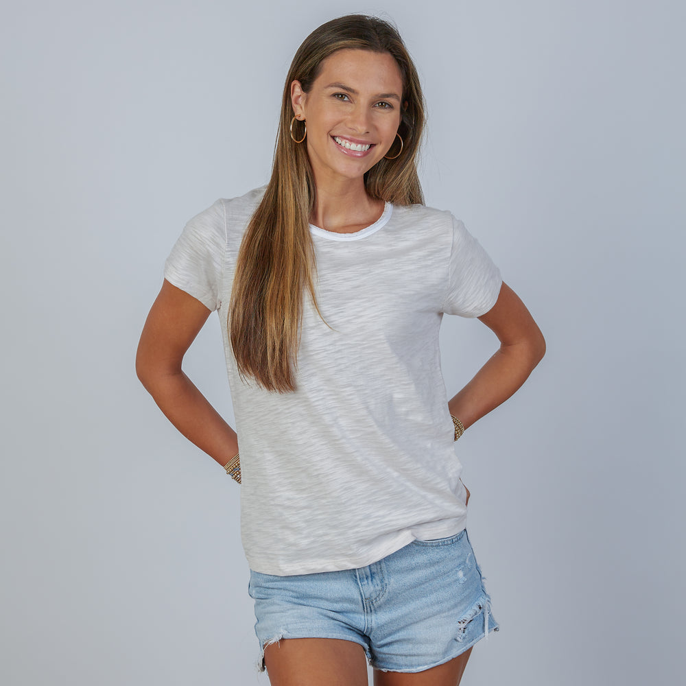 Woman wearing an erin gray design short sleeve rverse revel light heathered gray  t-shirt and denim shorts on a plain background