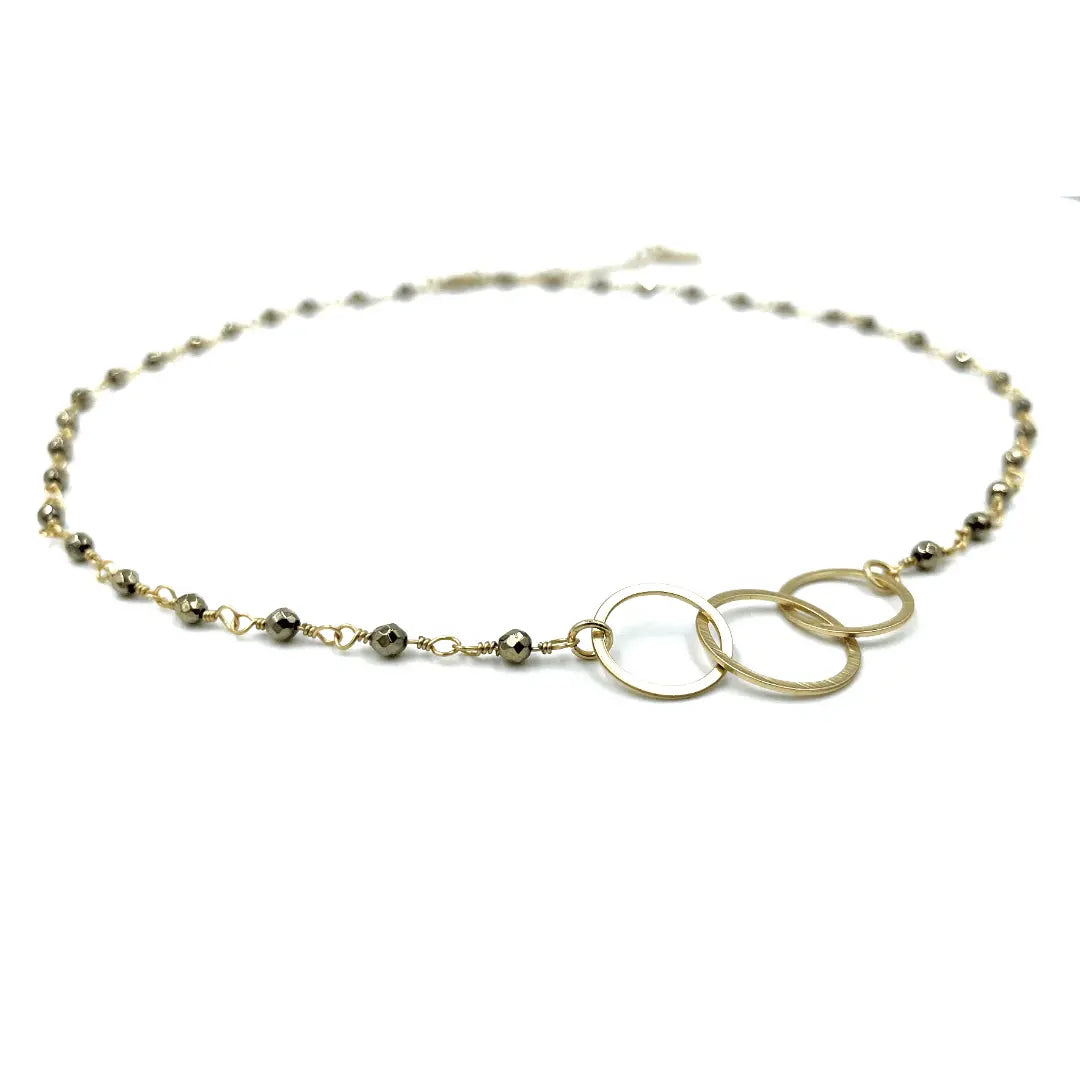 Erin Gray short necklace with three hoop charms on a pyrite chain, showcasing layered jewelry style and metallic finish.