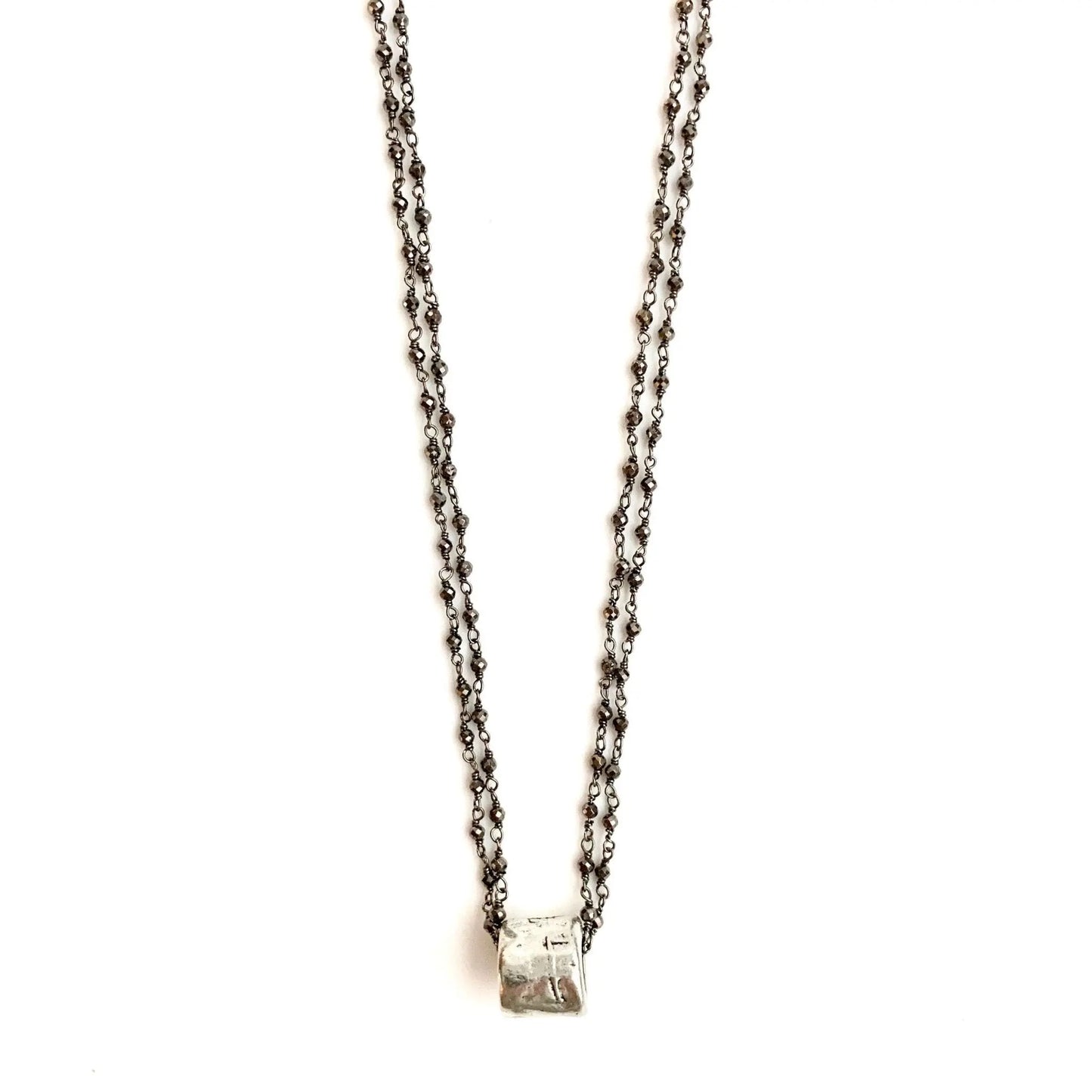 Silver barrel pendant on double oxi pyrite necklace by Erin Gray, showcasing a sleek jewelry design with textured metallic details.