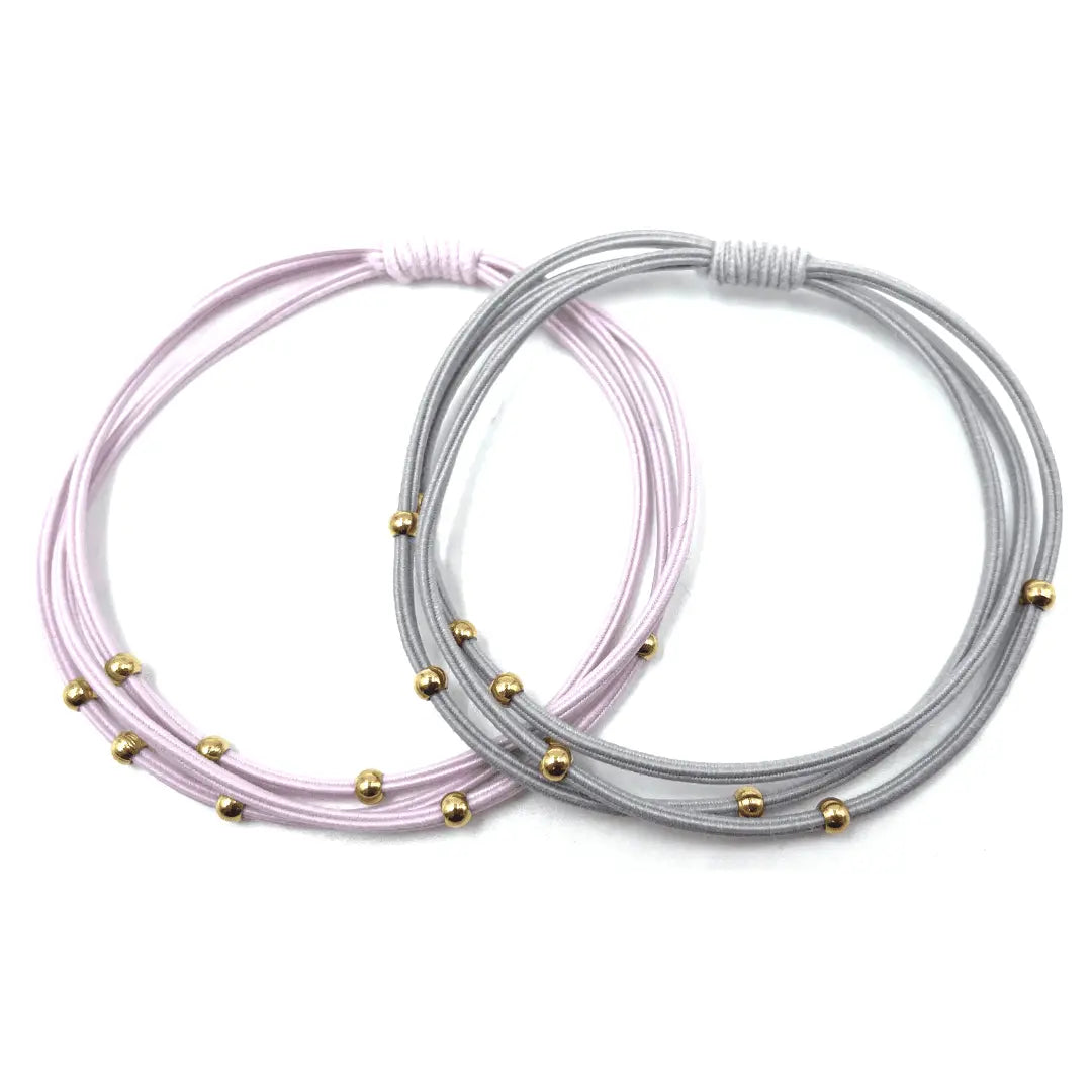 Waterproof 3mm gold water pony bracelet hair bands in gray and pink by erin gray, shown on a hair accessory display.